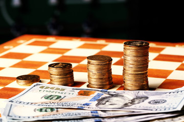 Tower coins and dollars on a chessboard, money