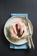 Scandinavian open sandwich with salad, prosciutto cotto, sun-dried tomatoes and thyme on plate....