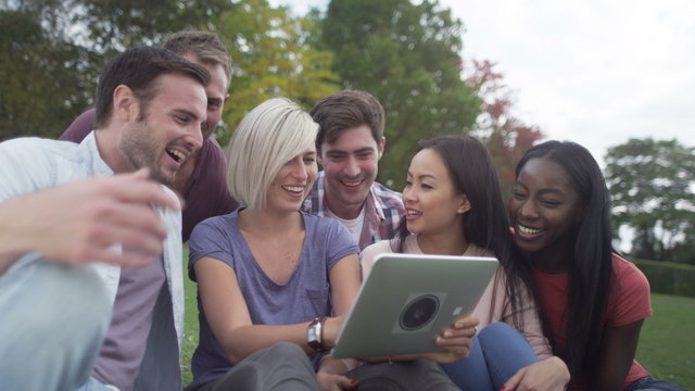  Happy group of friends in natural setting, pose for photo with computer tablet