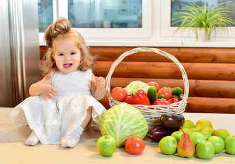 Fototapeta premium Beautiful little girl sitting surrounded by fresh fruits and veg