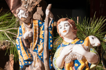 Obraz premium Painted pottery statue portraying a shepherd and his little sheep of a ceramic nativity scene by an artisan in Caltagirone