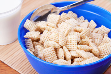 Bowl of Crispy Rice Cereal and Milk – A blue bowl full of rice cereal with a spoon. Milk in a glass in the background.