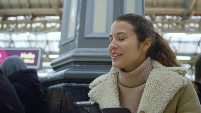  young attractive woman using an app on smart phone in a train station