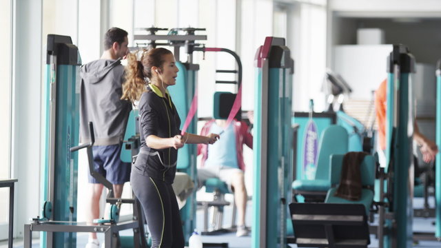  woman skipping in the gym with group of men using the machines in background