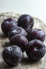 Mehrere frische Pflaumen auf Holz mit Wassertropfen