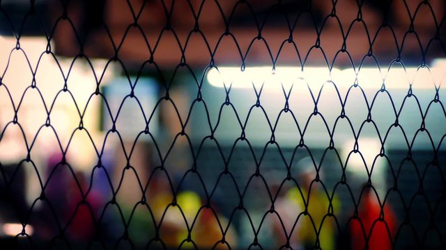 People In City At Night Through Fence Abstract