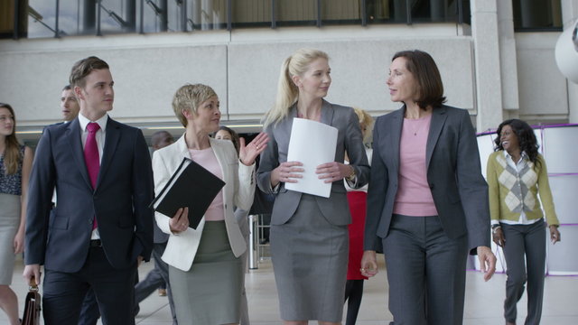  Large diverse business group talking as they walk through office building