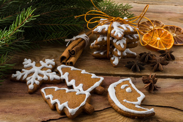 Christmas gift icing gingerbread, snowflake, fir tree and crescent cookies with cinnamon, anise, fruit slices, fir branches on a wooden background
