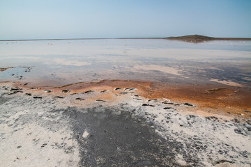 Salt pond with orange stains and clear blue sky