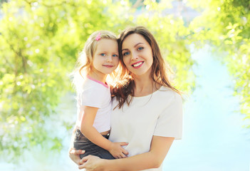 Portrait happy smiling mom hugging child daughter in summer day