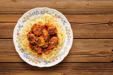 Yummy spaghetti with meatballs in tomato sauce on wooden table