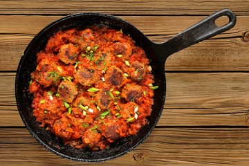 Homemade yummy meatballs in tomato sauce in cast iron pan