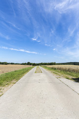 Fototapeta na wymiar small concrete road through fields in germany