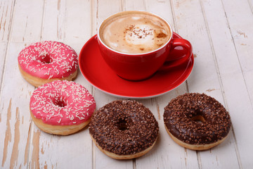 Cup of coffee and donuts on wooden surface  