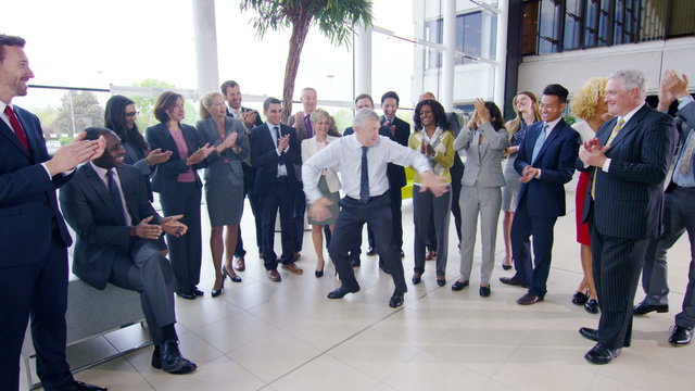 Self confident businessman doing funny dancing to entertain his colleagues