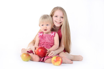 Fototapeta na wymiar adorable little two sisters 9 year and 1 year old with apple o
