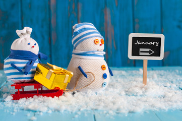 Word January written on direction sign and Snowman with red sled. Christmas, New year, winter decorations