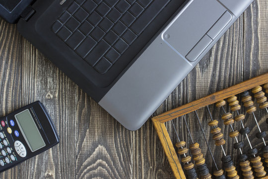 Notebook laptop bills and calculator lying on a wooden table. Background top view