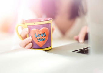 Girl holding tea cup and browsing internet at home