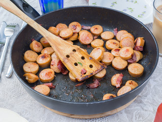 Kitchen pan with stir fried sausages and bacon