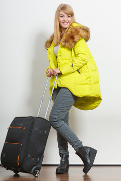 Happy young woman in warm jacket with suitcase.