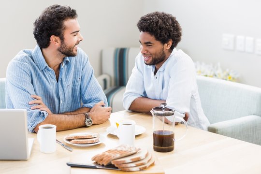 Happy gay couple having breakfast and talking