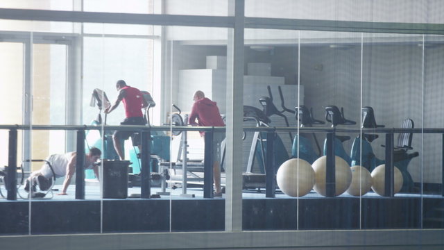  Long shot of group of men and one woman working out in the gym