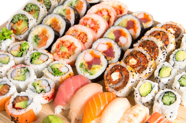 Assorted sushi rolls on a wooden board isolated on white backgro