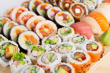 Assorted sushi rolls on a wooden board isolated on white backgro