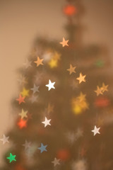 Defocused Christmas tree with bokeh shaped like stars.