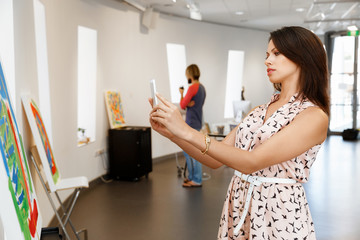 Young caucasian woman standing in art gallery front of  paintings