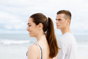 Young couple looking thoughtful while standing next to each other on beach