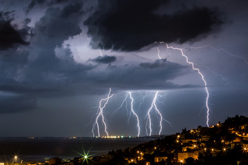 Fototapeta na wymiar Massive cloud to ground lightning bolts hitting the horizon of city lights 