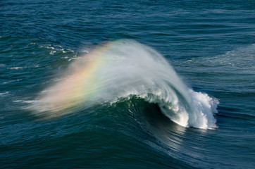 Welle mit Regenbogen bei Nazare, Portugal