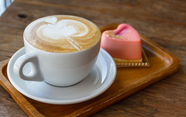 Close up cup of Coffee, latte on the wooden table with mousse rose cake heart shaped