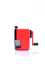 red rotary pencil sharpener with black pencil isolated on white background