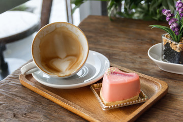 Close up cup of Coffee, latte on the wooden table with mousse rose cake heart shaped