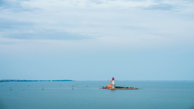 Beautiful sunset on coastline with powerful lighted lighthouse; Beidaihe, China.