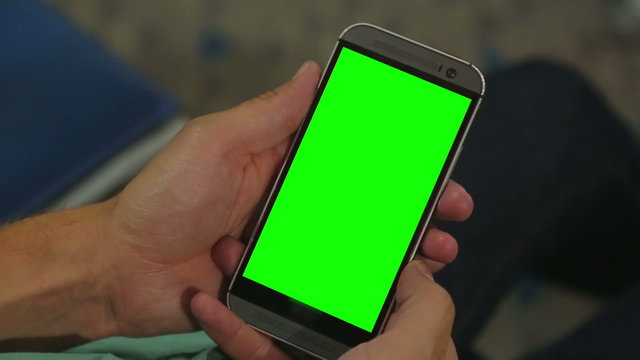 Closeup of male hands holding smart phone with green screen prekeyed for effects