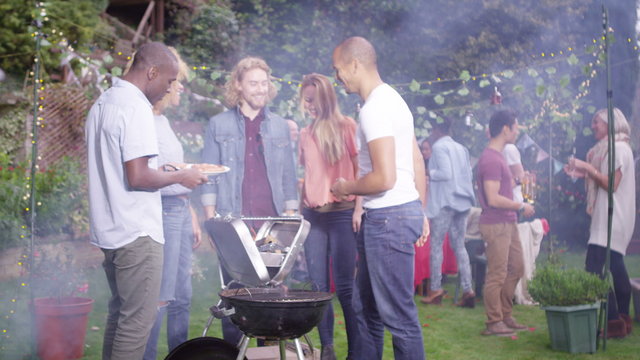  Happy mixed ethnicity group of friends chatting & having fun at bbq party. Shot on RED Epic.