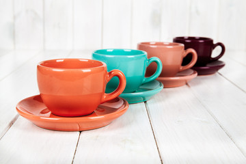 colored cups on a wooden white background. coffee concept