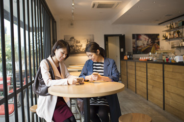 Two women looking at smart phone in cafe