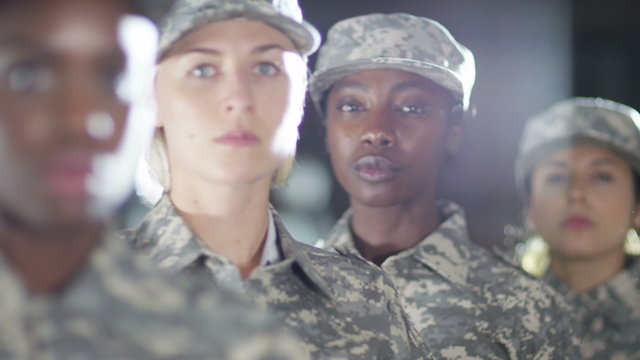  Close up on faces of mixed ethnicity female soldiers standing to attention and saluting. 