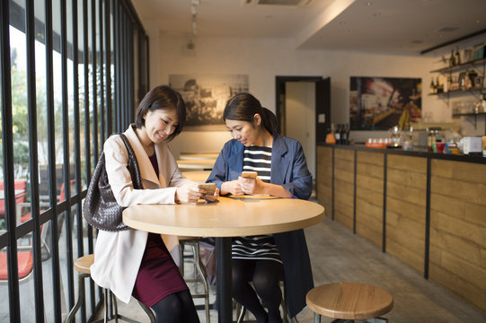 Two women looking at a mobile phone in a cafe