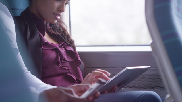 Beautiful woman on train journey looking at computer tablet