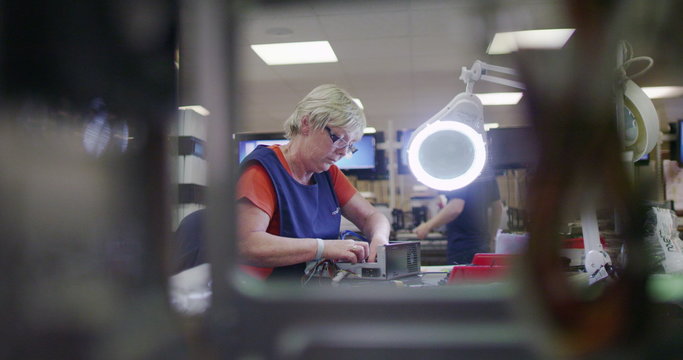 Female worker in electronics factory working on computer testing and repairs
