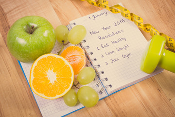 Vintage photo, New years resolutions written in notebook and fruits, dumbbells with centimeter