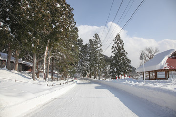 Fototapeta premium Snow road near Gozaishi shrine located by Lake Tazawa in Akita,
