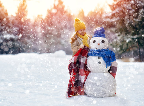 girl playing with a snowman
