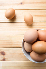 hen eggs in bowl on wood plate